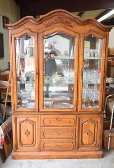 an old china cabinet with glass doors in a room filled with other furniture and items