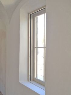 an empty room with white walls and a window on the wall is seen from outside