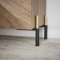 two black and gold handles on a wooden cabinet in a room with hardwood flooring