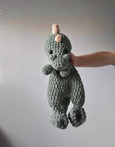 a crocheted stuffed animal being held in the air by someone's hand