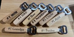 six wooden bottle openers with engraved names and numbers on them sitting on a table