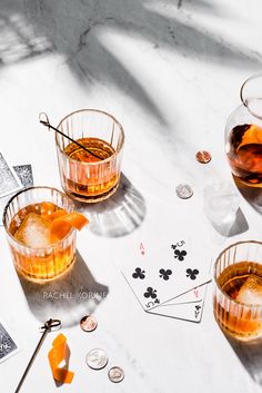 two glasses filled with liquid sitting on top of a table next to playing cards and dice