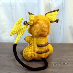 a crocheted yellow stuffed animal sitting on top of a wooden table