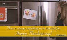 a woman standing in front of a refrigerator with thanksgiving decorations on the door and an orange towel hanging from it's handle