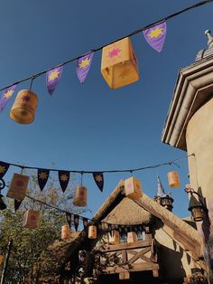 some paper lanterns hanging from a line over a building and trees with blue sky in the background