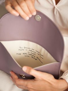 a woman is holding a pillow with writing on it and the inside of her purse