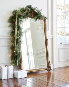 a large mirror sitting on top of a wooden floor next to a christmas wreath and presents