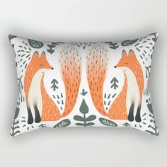 an orange and white pillow with two foxes on it's sides, sitting next to each other