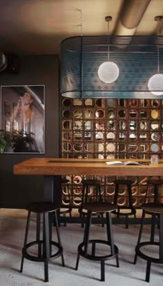 a table with stools in front of a wall full of wine bottles and corks