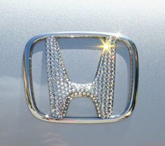 the front grille of a silver car with diamonds on it's grill and logo