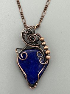 Stunning Lapis Lazuli blue teardrop pendant wrapped in oxidized copper wire to give it an antique look. Features wire weaving and copper beads. Pendant is 2.25 inches tall and 1.25 inches wide. Comes with a free chain! Blue Copper Pendant Necklace, Wire Wrapped Teardrop Copper Jewelry, Copper Teardrop Wire Wrapped Jewelry, Wire Wrapped Copper Wire Teardrop Pendant Necklace, Blue Copper Wire Wrapped Necklaces, Blue Copper Wire Pendant Necklace, Blue Pendant Necklace With Copper Wire, Teardrop Copper Wire Wrapped Jewelry, Blue Copper Wire Wrapped Necklace