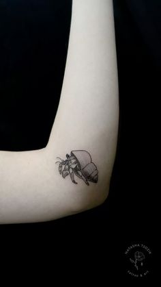 a black and white photo of a tattoo on the arm with a bug in it