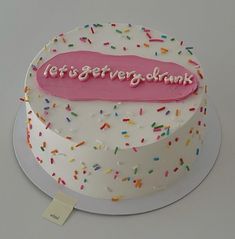 a white cake with sprinkles and a pink sign