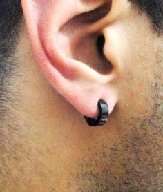 a close up of a man's ear with a black ring on it