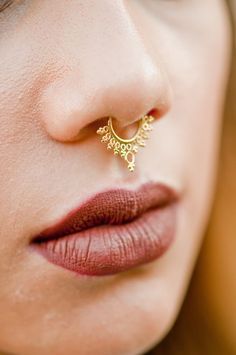 a close up of a woman's nose with a gold nose ring on it