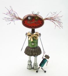 a metal statue with a bottle and some keys on it's legs, holding a sign that says welcome