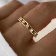 a woman's hand with a gold ring and three diamond rings on top of it