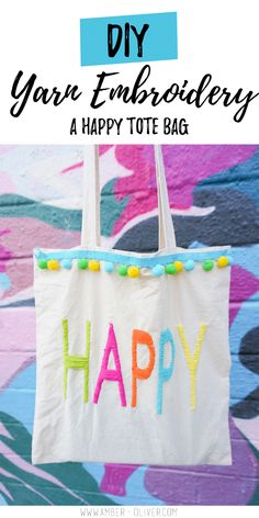 an embroidered happy tote bag hanging on a wall with the words, diy yarn embroidery