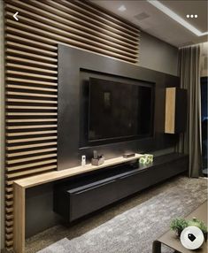 a living room with a large television on the wall and wooden slats behind it