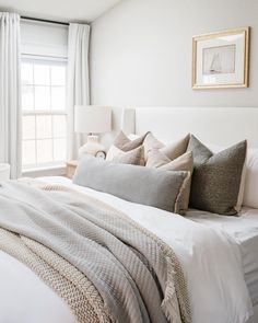 a bed with white sheets and pillows in a bedroom