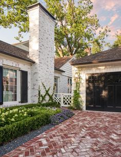 a brick driveway leading to a white house