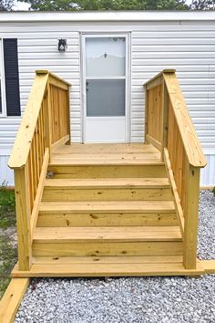 wooden steps lead up to the front door of a mobile home