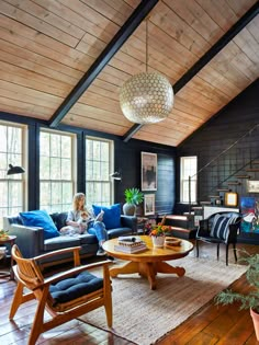 a woman sitting on a couch in a living room with blue furniture and wood floors