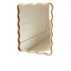 a mirror that is on the wall with a white background and some light brown trim