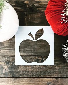 an apple cut out on top of a piece of paper next to a red pillow