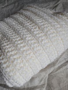 a white knitted blanket laying on top of a bed