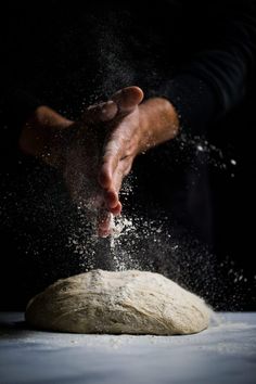 a person is sprinkling flour onto a doughnut