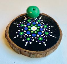 a small green object sitting on top of a piece of wood