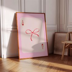 a pink card with a red bow on it sitting in front of a wooden chair