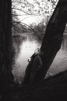 a man standing next to a tree near a body of water