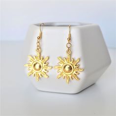 A pair of radiant gold sun earrings featuring bright gold tone dangle charms and earwires. Gold charms are plated alloy. Each set comes with a pair of rubber backs and ear wires are hypoallergenic and nickel free. Please be advised - if your ears are extremely sensitive, they are NOT sterling silver. Jewelry Care Tips For a Long, Happy Life Together <3 * Store your jewelry in an air-tight container to avoid metal parts becoming tarnished or oxidized * Remove Jewelry before exercise or swimming * Gold Celestial Nickel-free Earrings, Nickel Free Gold Earrings For Summer, Nickel-free Gold Celestial Earrings, Gold Sunburst Earrings With Sun Design, Gold Celestial Earrings With Sun Design, Gold Sunburst Earrings For Gift, Gold Brass Earrings With Sun Design, Gold Drop Earrings With Sun Design, Gold Jewelry With Sun Design Drop Earrings