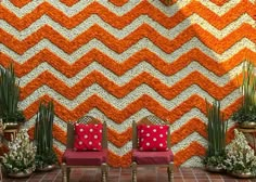 two red chairs sitting next to each other in front of an orange and white wall