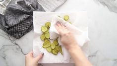 a person is peeling cucumbers on a white towel and some other items are sitting on the table