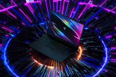 an open laptop computer sitting on top of a purple and blue background with neon lights