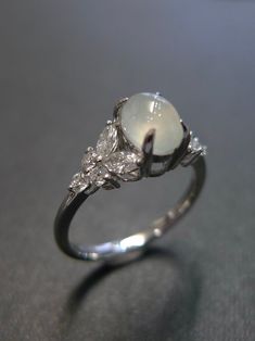 a close up of a ring on a table with a diamond and white stone in the middle