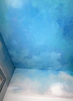 an empty room with blue walls and clouds painted on the ceiling