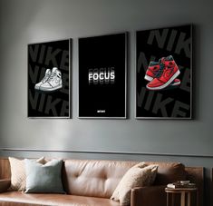 three posters hang on the wall above a couch in a room with a brown leather sofa