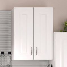 a kitchen with white cupboards and appliances next to a wall mounted potted plant