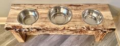 three stainless steel bowls are placed on a wooden stand that is made out of wood