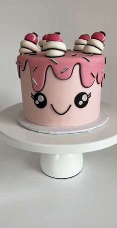 a pink cake with white frosting and sprinkles on top is sitting on a pedestal