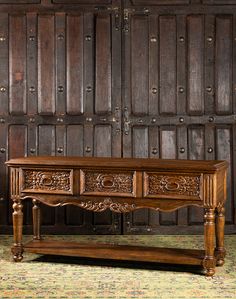 an old wooden table with two drawers in front of wood paneled walls and flooring