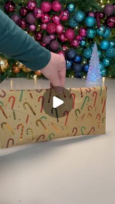 a person opening a christmas gift box with candy canes on it