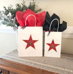 two bags with red and black stars on them sitting on a table next to a potted plant