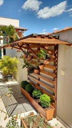 an outdoor garden area with potted plants on the wall and wooden trelliss