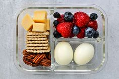 a plastic container with crackers, cheese, strawberries, and other food items