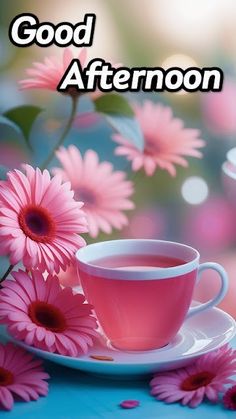 a cup of tea and pink flowers on a blue tablecloth with the words good afternoon